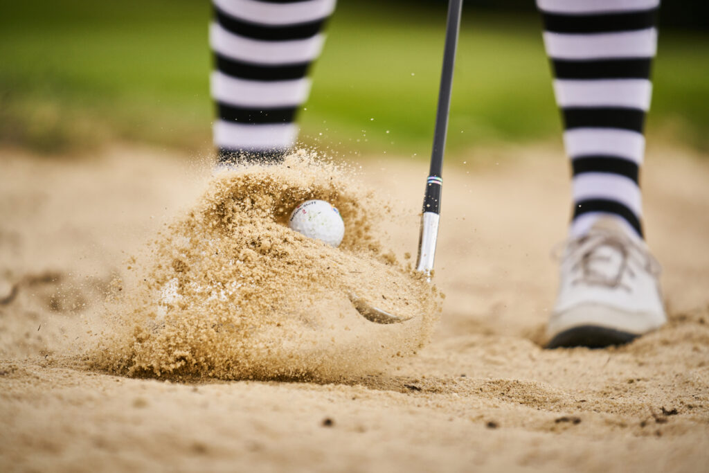 golf ball being hit out of a sandbank