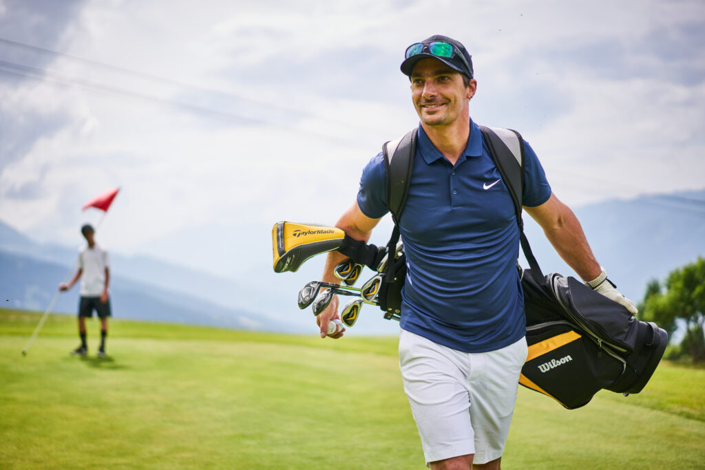 golfer walking with his golf clubs hanging off his shoulders